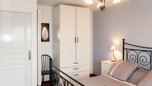 Ein Schlafzimmer mit Bett, Schrank, Stuhl, Nachttisch mit Lampe und einer Deckenleuchte.