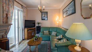 A living room with a green sofa, a wooden coffee table, a television, and a lamp. - Gueradur by Interhome (Pleumeur Bodou)