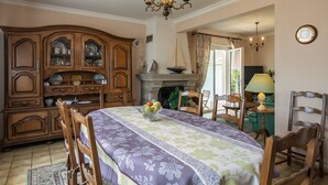 A dining room with a large wooden cabinet, a fireplace, and a chandelier. - Gueradur by Interhome (Pleumeur Bodou)