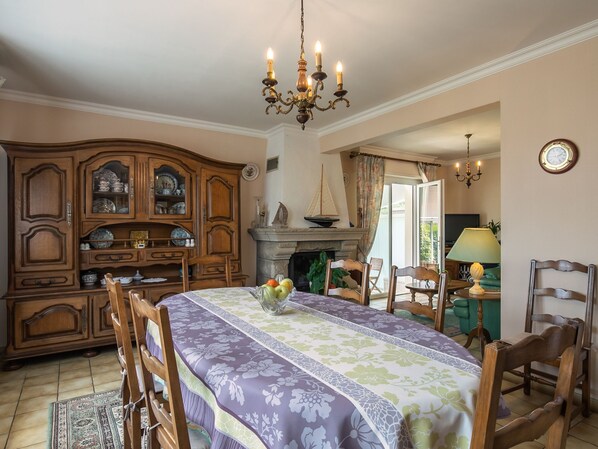 Een eetkamer met een grote houten kast, een open haard en een kroonluchter.
