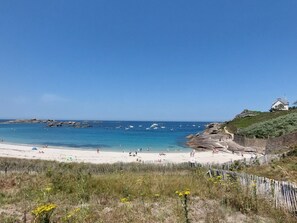 A beach with clear skies, rocky outcrops, and a white building on a hill. - Gueradur by Interhome (Pleumeur Bodou)