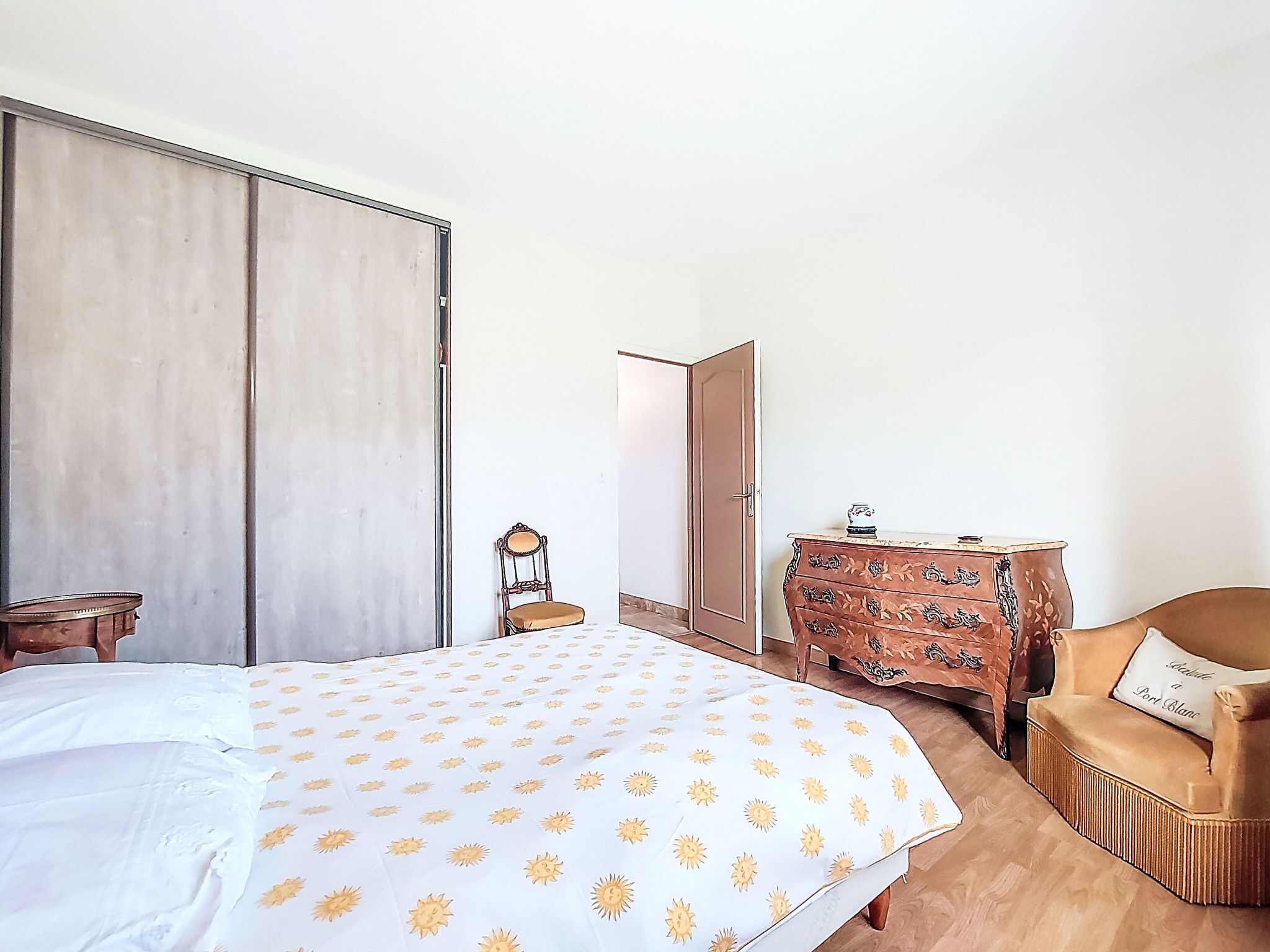 Une chambre à coucher comprenant un lit, une commode en bois, une chaise et une armoire.