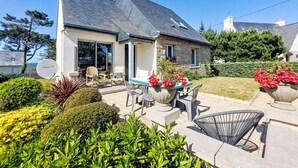 A house with a stone exterior, a large patio with outdoor furniture, and a garden with various plants and flowers. - Les Courlis by Interhome (Trévou-Tréguignec)