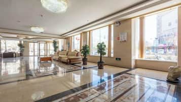 Un vestíbulo amplio con piso pulido, una mesa de recepción y un sofá.