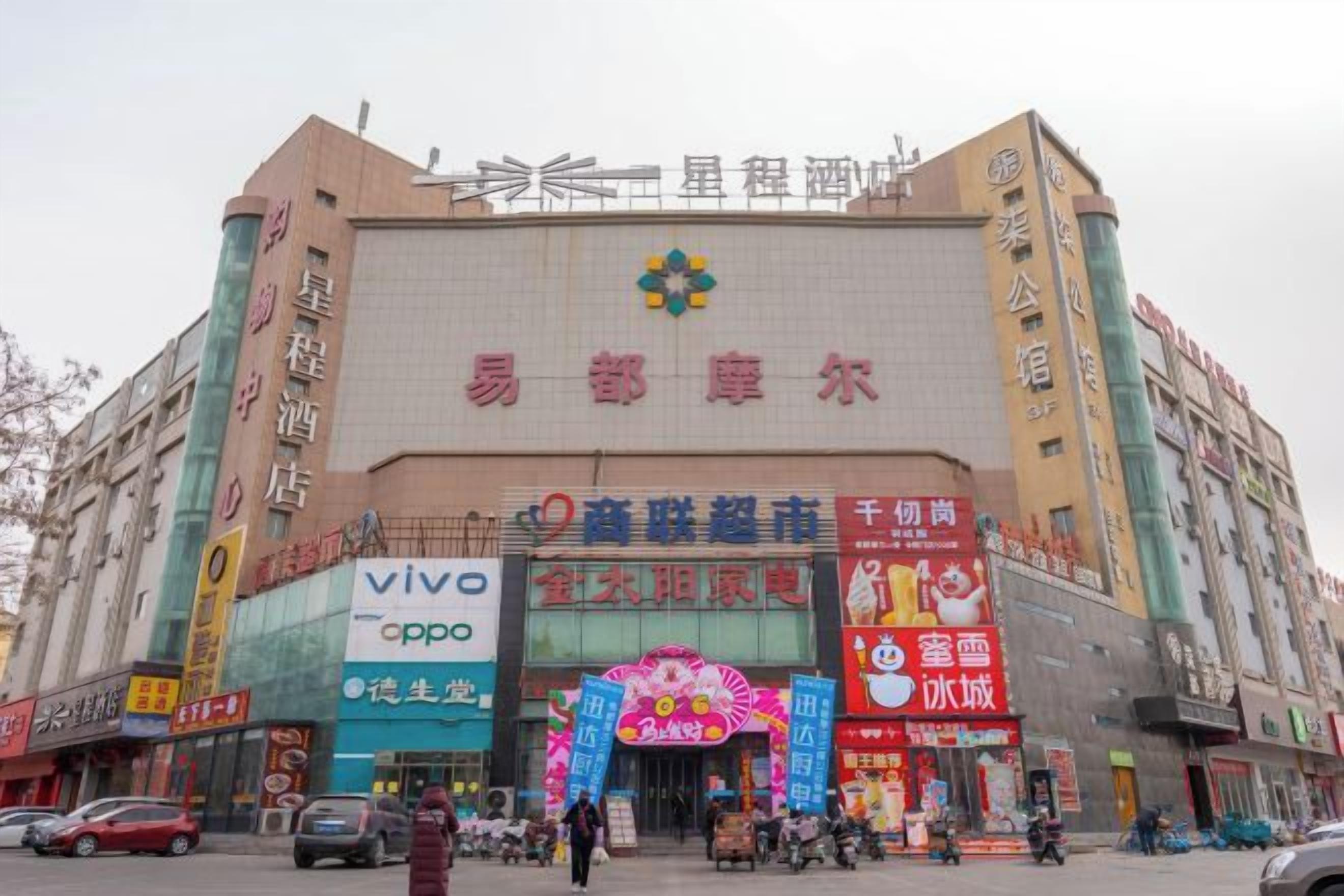 A large building with multiple signs, including 'vivo' and 'oppo' advertisements, and a prominent entrance with a colorful arch.