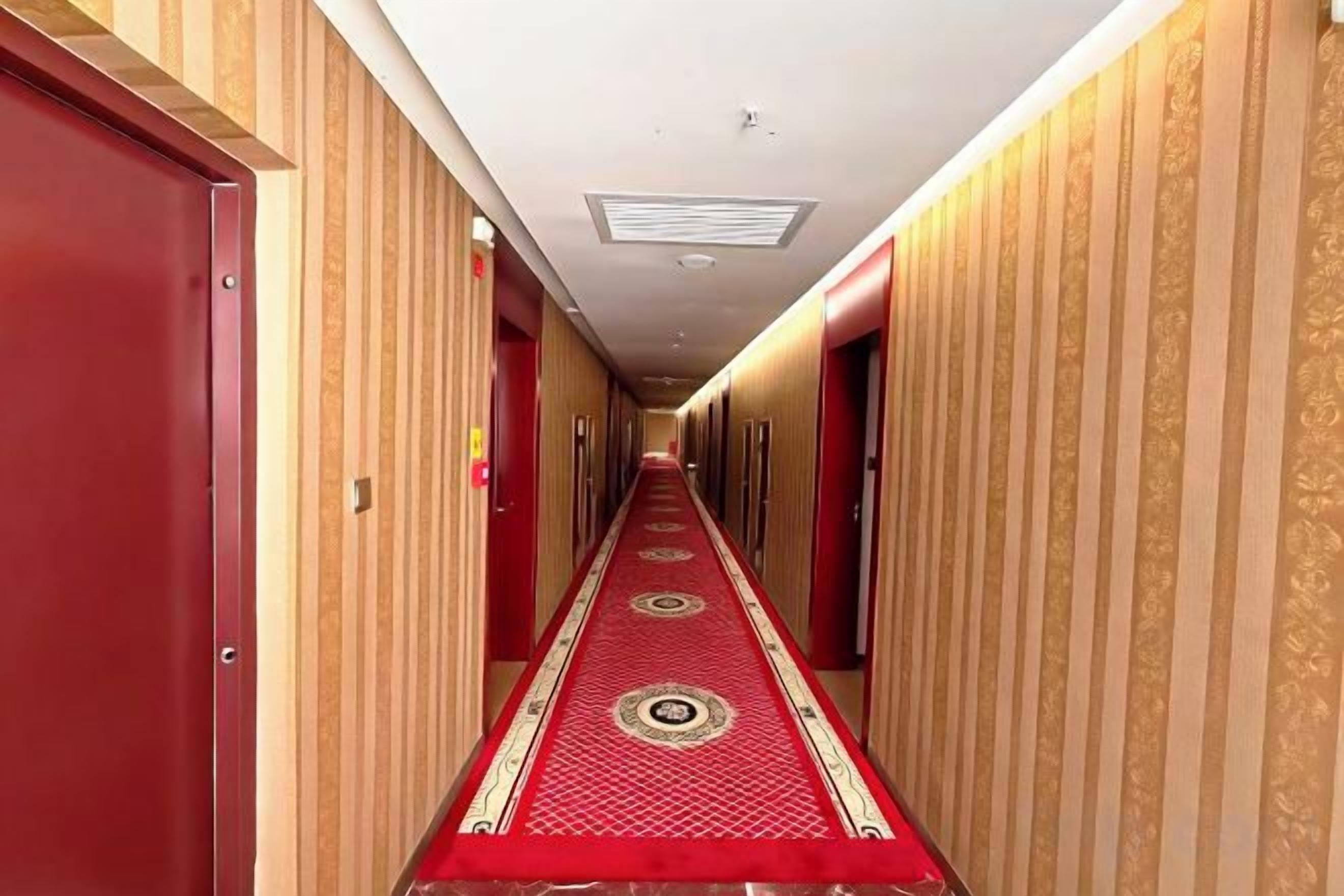 Un pasillo de hotel con alfombra roja, paneles de madera y puertas a ambos lados.