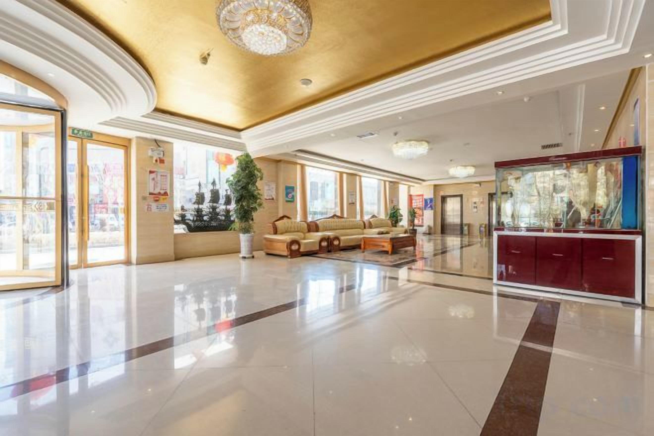 A spacious lobby with a high ceiling, a seating area, and a reception desk.