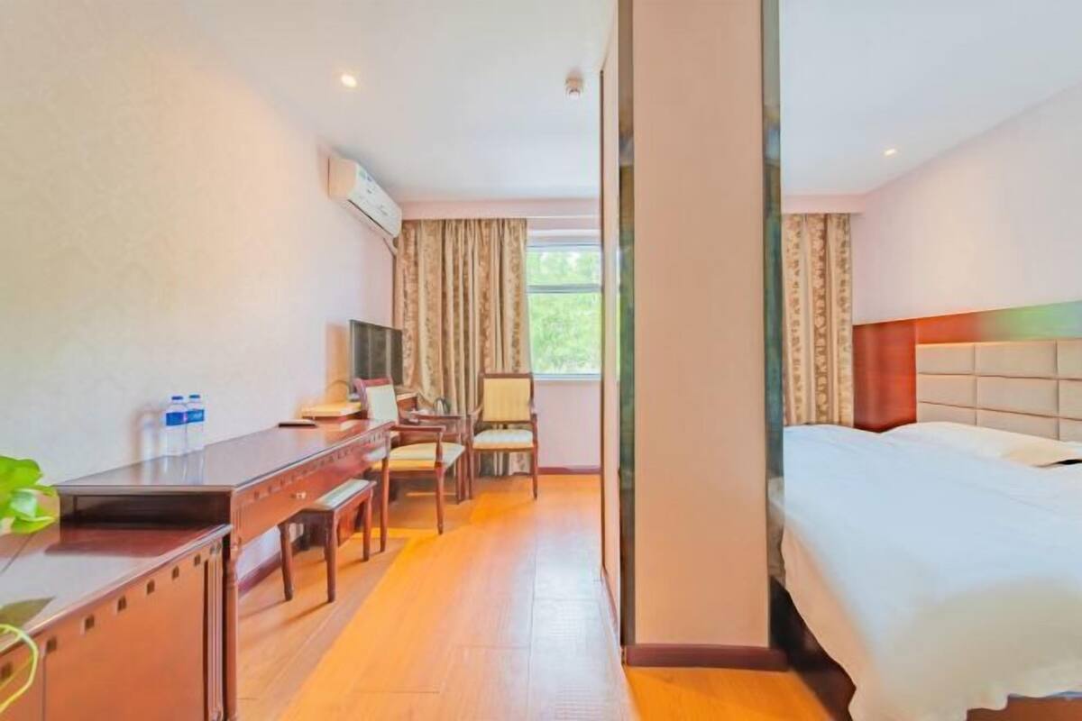 Een hotelkamer met een bed, een bureau, een stoel, een televisie en een raam met gordijnen.