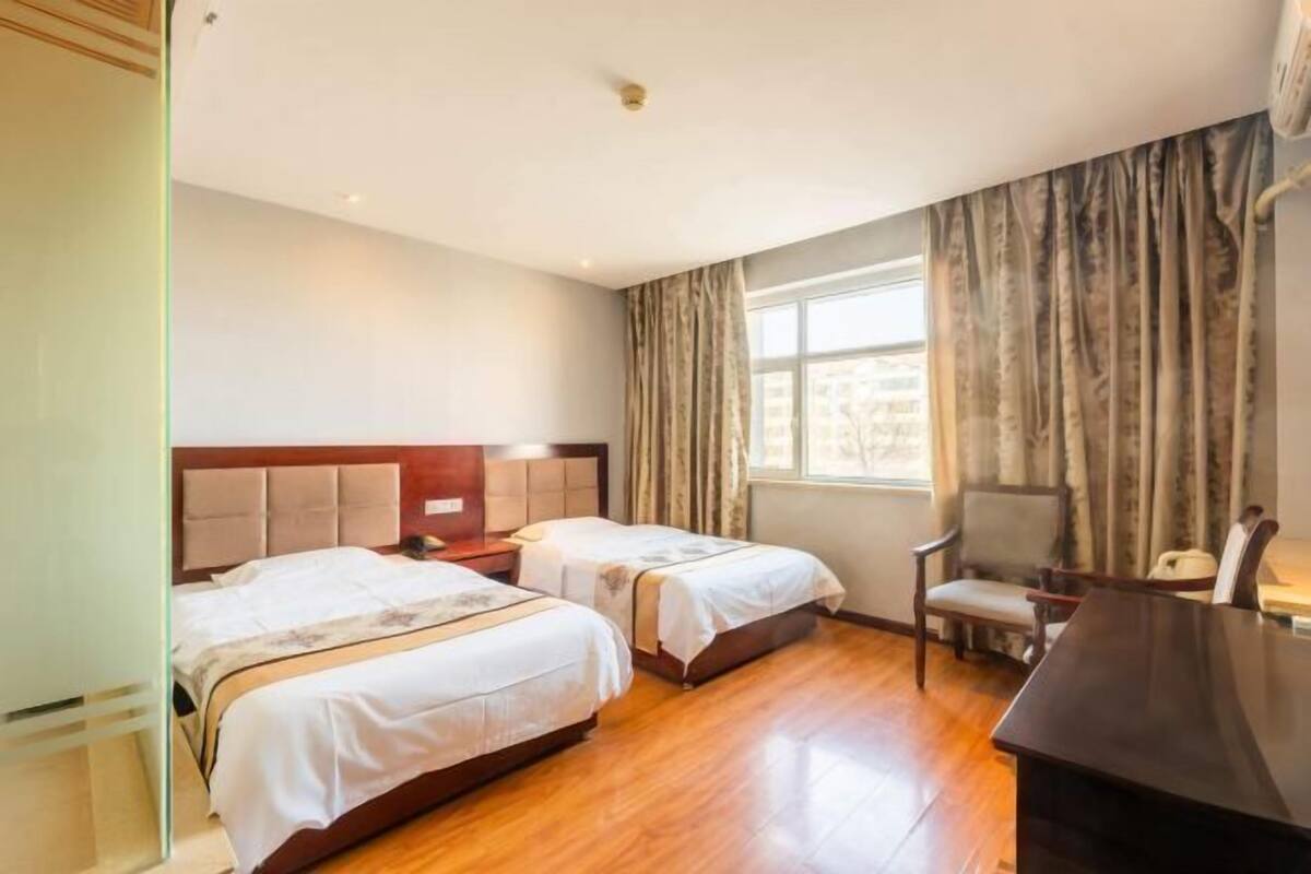 Een hotelkamer met twee bedden, een bureau en een stoel.