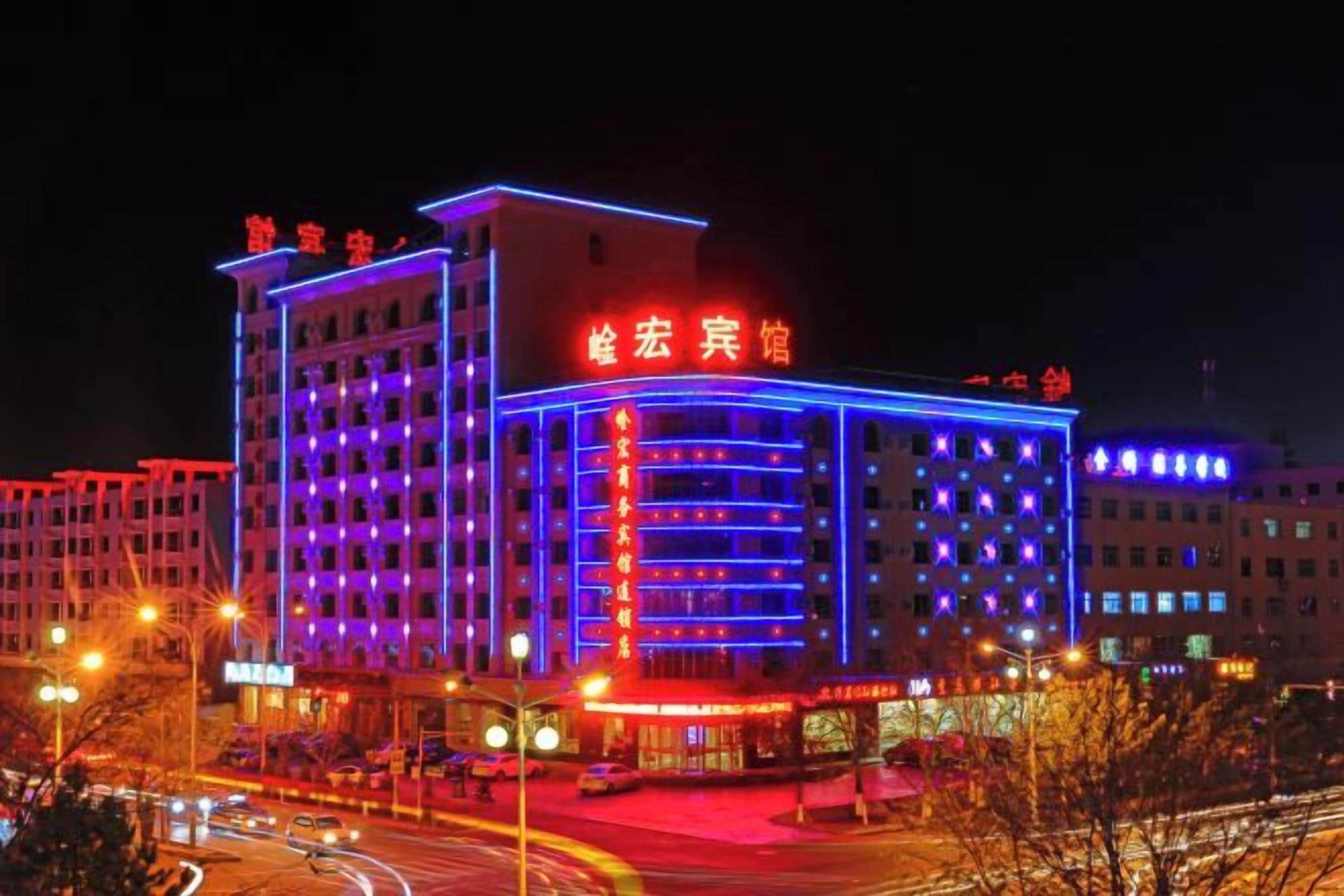 Un hotel de varios pisos con letreros iluminados y una entrada destacada.