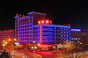 Un hotel de varios pisos con letreros iluminados y una entrada destacada.