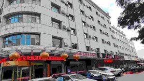 A multi-story building with several ground-floor shops and parked cars. - Yanhong Hotel (Jiayuguan Xiongguan Plaza) (Jiayuguan)