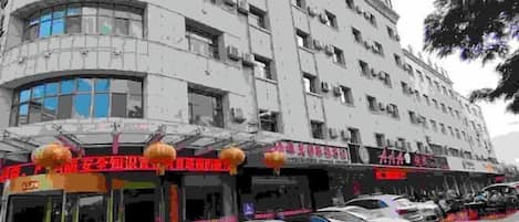 Un edificio de varios pisos con tiendas en la planta baja y coches aparcados.