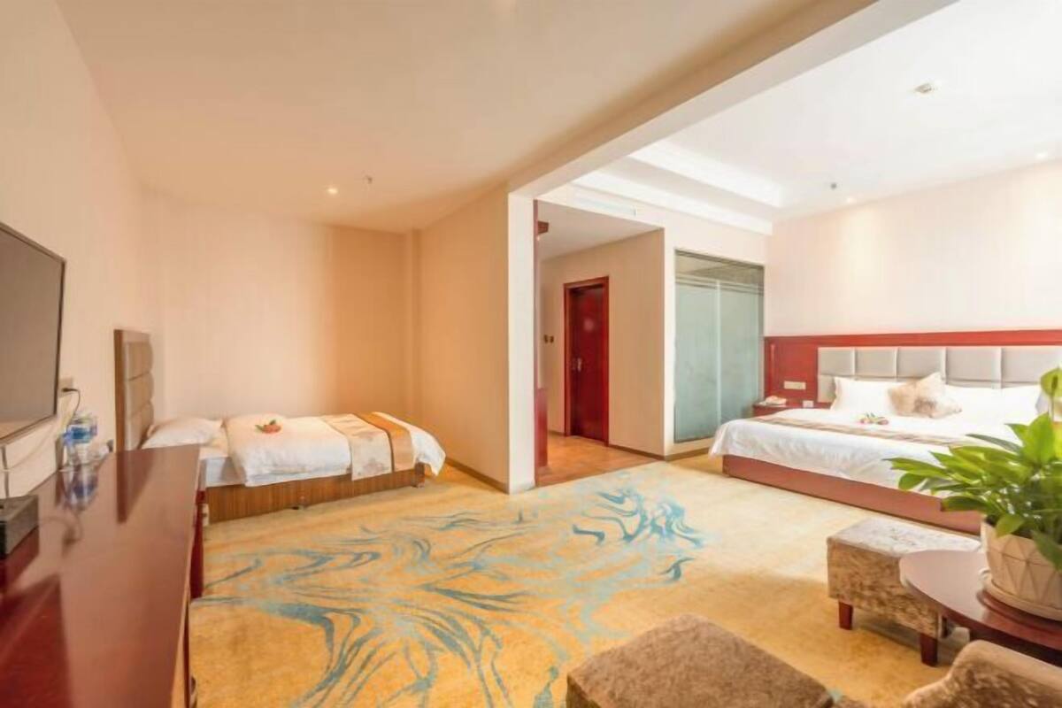 Een hotelkamer met twee bedden, een televisie, een bureau en een groot raam.