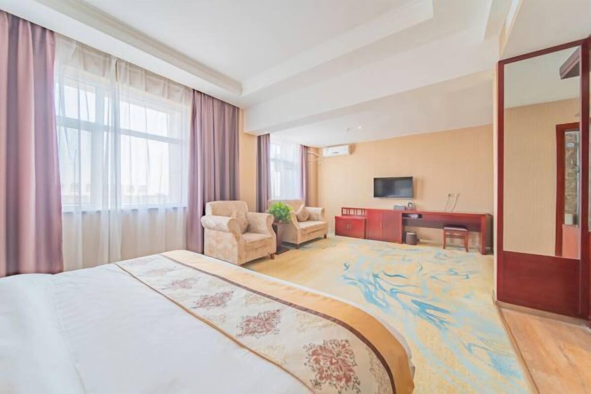 Een hotelkamer met een groot bed, een bureau, een stoel, een televisietoestel en een kledingkast.