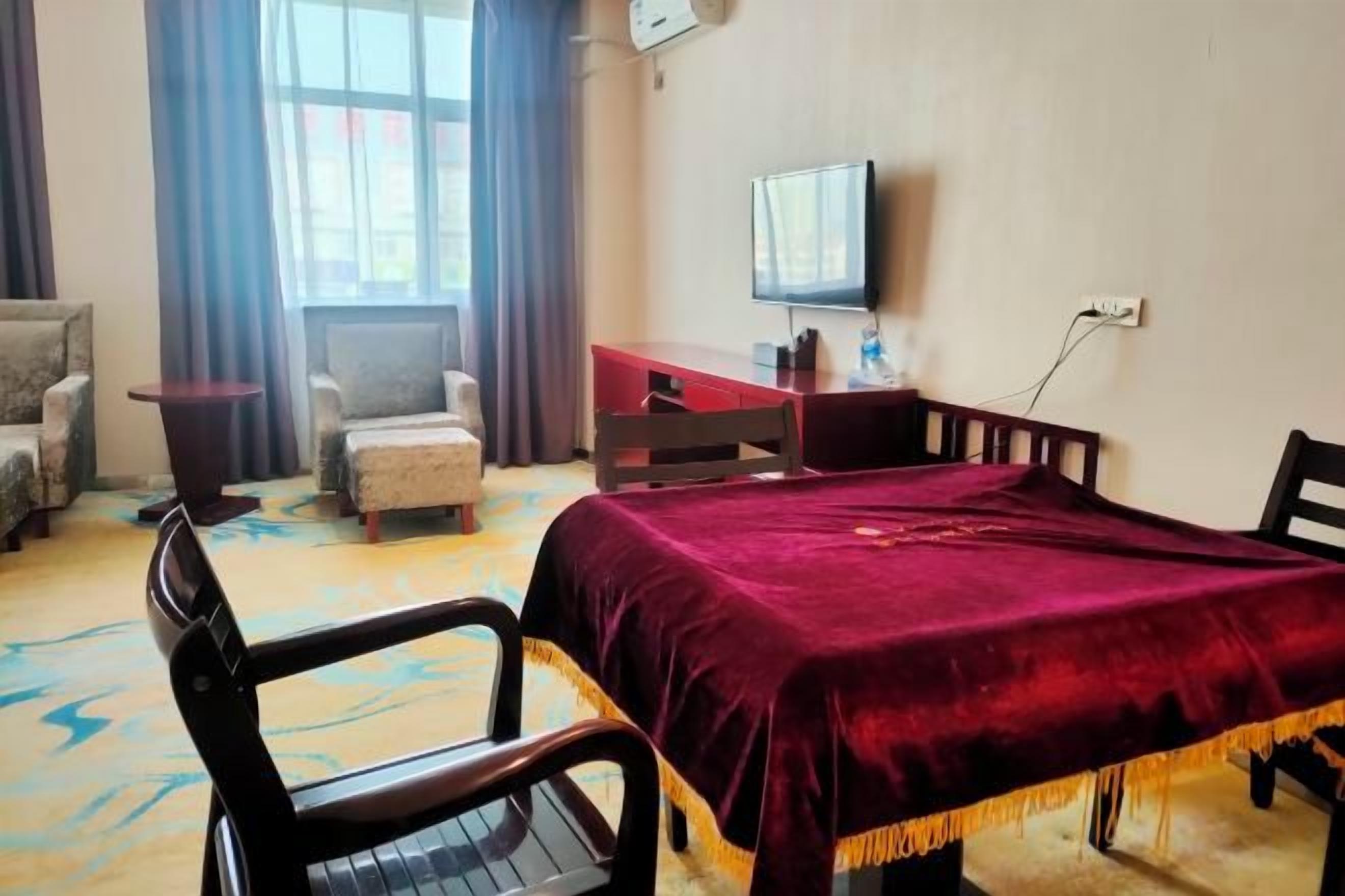 Habitación de hotel con cama, escritorio, silla, televisor y ventana.