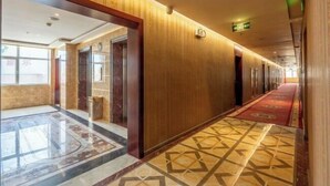 A hotel corridor with wooden paneling, a patterned carpet, and a marble floor. - Yanhong Hotel (Jiayuguan Xiongguan Plaza) (Jiayuguan)