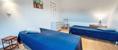 Ein Zimmer mit zwei Betten, einem Schreibtisch, einem Stuhl und einem kleinen Tisch.