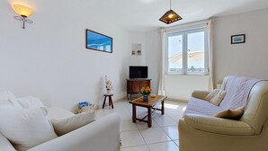 Un salon avec un canapé, une table basse, un téléviseur et une fenêtre donnant sur un beau paysage.