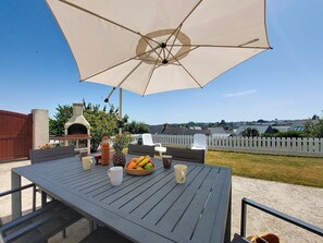 Une terrasse extérieure avec une table, des chaises, un parasol, un barbecue et une vue sur le quartier.