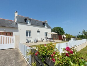 Une maison à deux étages dotée d’un patio, d’un espace salon extérieur et d’un coin barbecue.