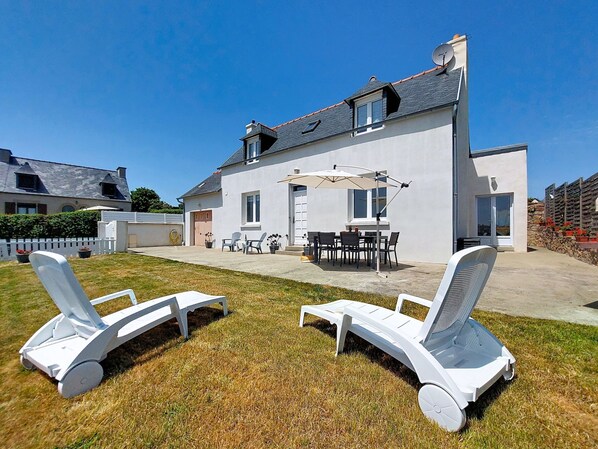 Une maison moderne dotée d’un patio, de meubles d’extérieur et d’une antenne parabolique.