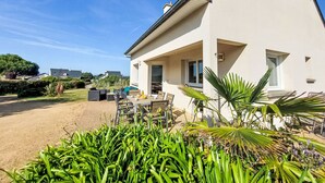 A modern house with a patio area featuring outdoor furniture and plants. - de la Plage by Interhome (Pleubian)