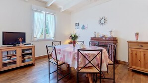 Un espace repas comprenant une table, des chaises, un téléviseur et une bibliothèque.
