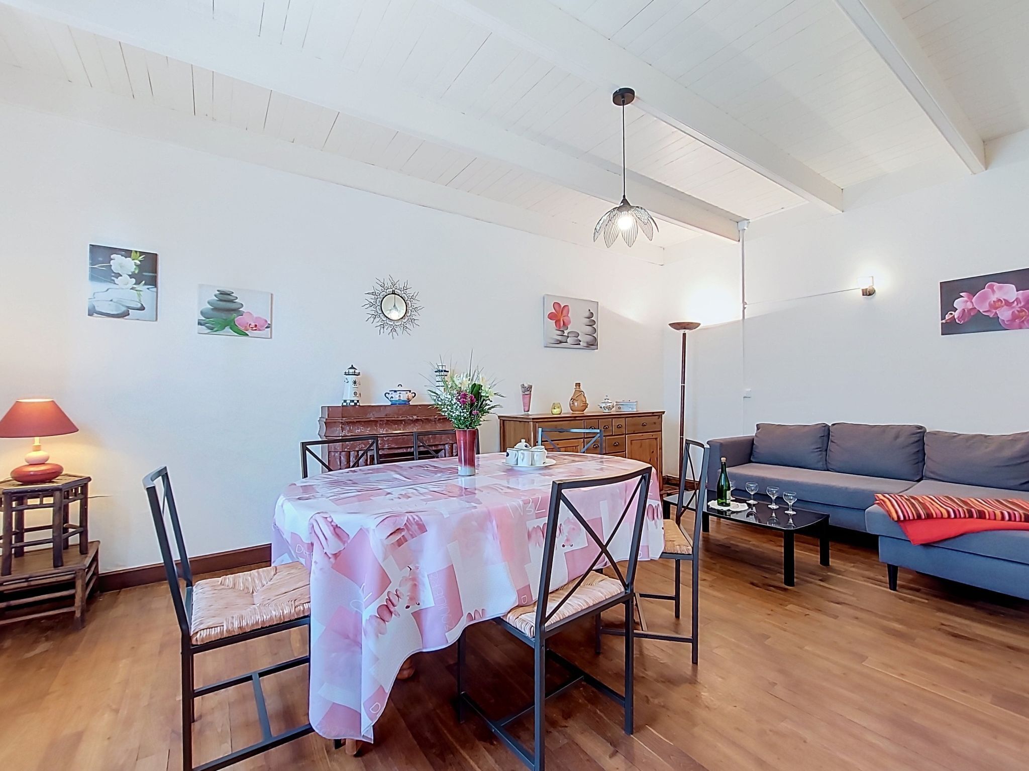 Un comedor con mesa y sillas, un sofá, una lámpara y decoración en la pared.