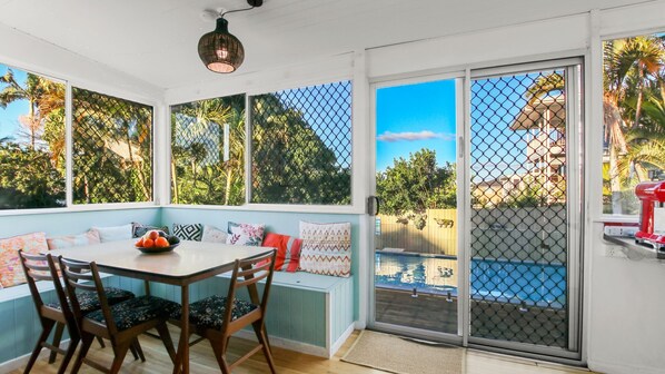 Enjoy a meal or relax in this sunroom with a view of the pool and lush surroundings.