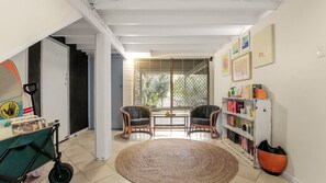 Relax in this open-plan living space with a high ceiling, featuring a central area with two chairs and a bookshelf.