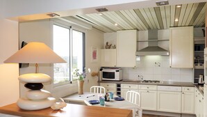 A modern kitchen with white cabinets, a wooden countertop, and a dining area with a table and chairs.