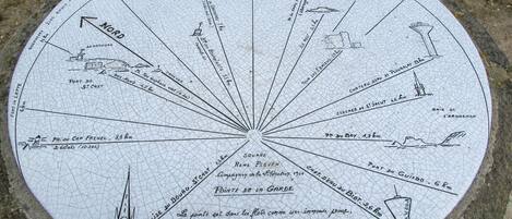 A circular stone map with various landmarks and distances marked, including 'NORD' and 'POINTE DE LA GARDE'.