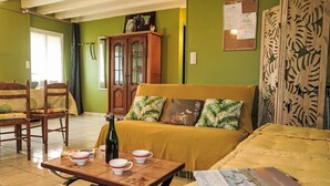 A cozy room with a bed, a wooden table with cups and a bottle, a cabinet, and a patterned curtain. - L'Egven by Interhome (Saint Cast le Guildo)