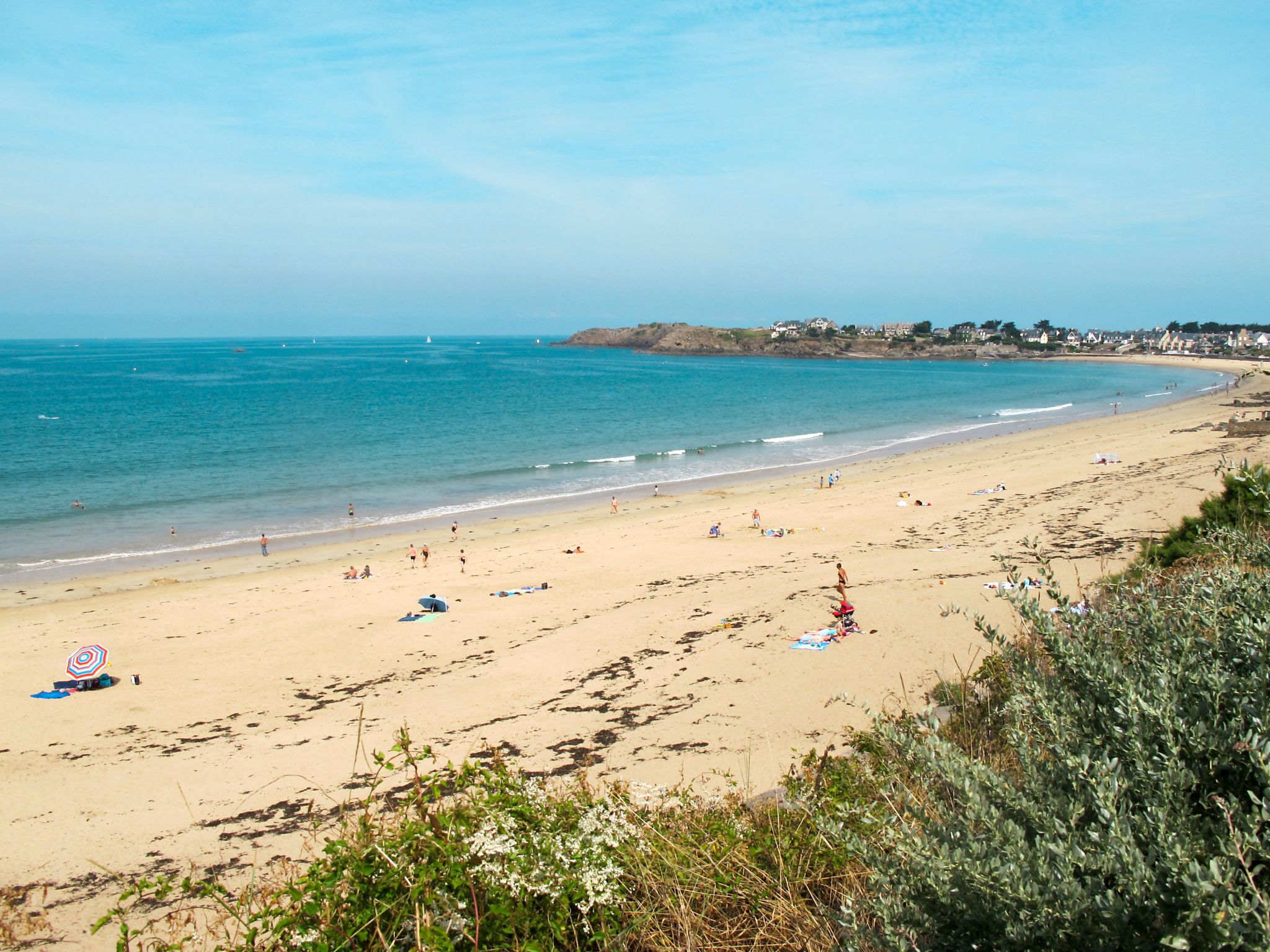 A beach with clear skies, sandy shore, and a few umbrellas.