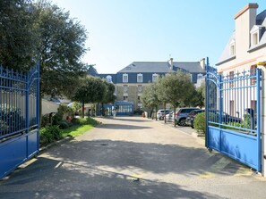 A gated driveway leading to a building with a stone facade and multiple windows.