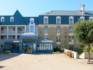 Un hotel con fachada azul, una estructura cúpula central y un edificio de piedra con múltiples ventanas.