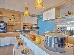 Una barra de desayuno moderna con una máquina de café, cestas de mimbre y una olla de acero inoxidable grande.