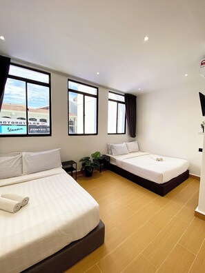 A hotel room with two beds, a potted plant, and large windows offering a city view. - The 6N by Sky Hive (George Town)