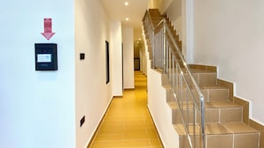 Un pasillo de hotel con una escalera, un lector de tarjetas de acceso y un cartel que indica la zona de recepción.