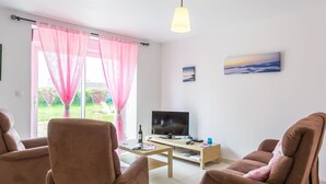 A living room with two brown sofas, a wooden coffee table, a TV, and a window with pink curtains. - Va Zi Bihan by Interhome (Guissény)