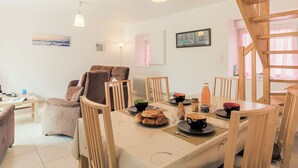 A dining area with a table set for breakfast, including croissants and coffee, in a bright room with wooden furniture and a staircase. - Va Zi Bihan by Interhome (Guissény)
