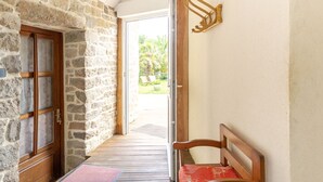 A stone-walled hallway with a wooden bench and a door leading outside. - Les Bambous by Interhome (Guissény)