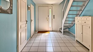 A hallway with a staircase, white doors, and a light fixture.