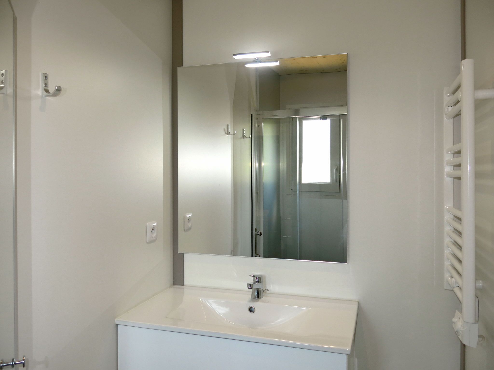 A bathroom with a white sink, a mirror, and a towel rack.