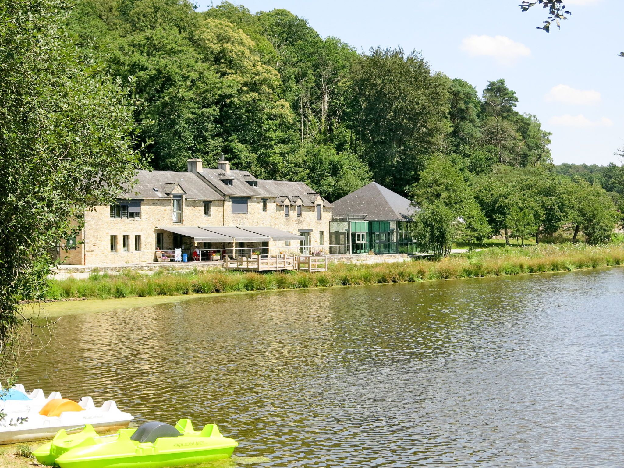 Hotel a la orilla del río con terraza y barcos.