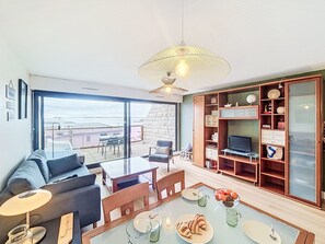 Una sala moderna con un gran ventanal, un comedor y un mueble para televisión.