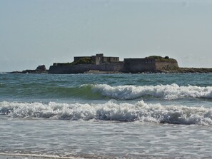 Una fortificación costera con un muro de piedra y un pequeño edificio, con vista al mar.
