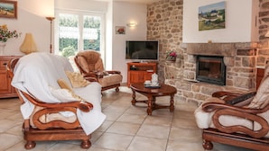 A cozy living room with a stone fireplace, wooden furniture, and a television. - Ty Breiz by Interhome (Ploemeur)