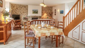 A cozy dining area with a stone wall, wooden furniture, and a fireplace. - Ty Breiz by Interhome (Ploemeur)